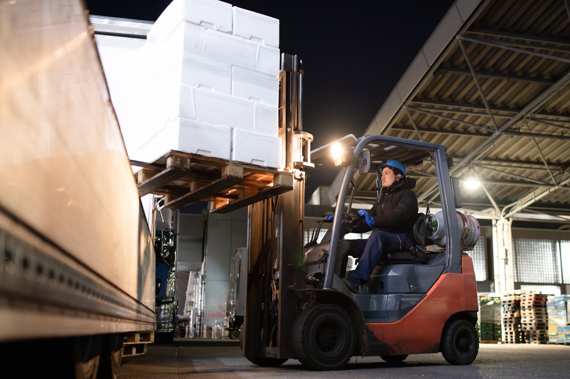 A man riding a forklift and loading cargo onto a truck