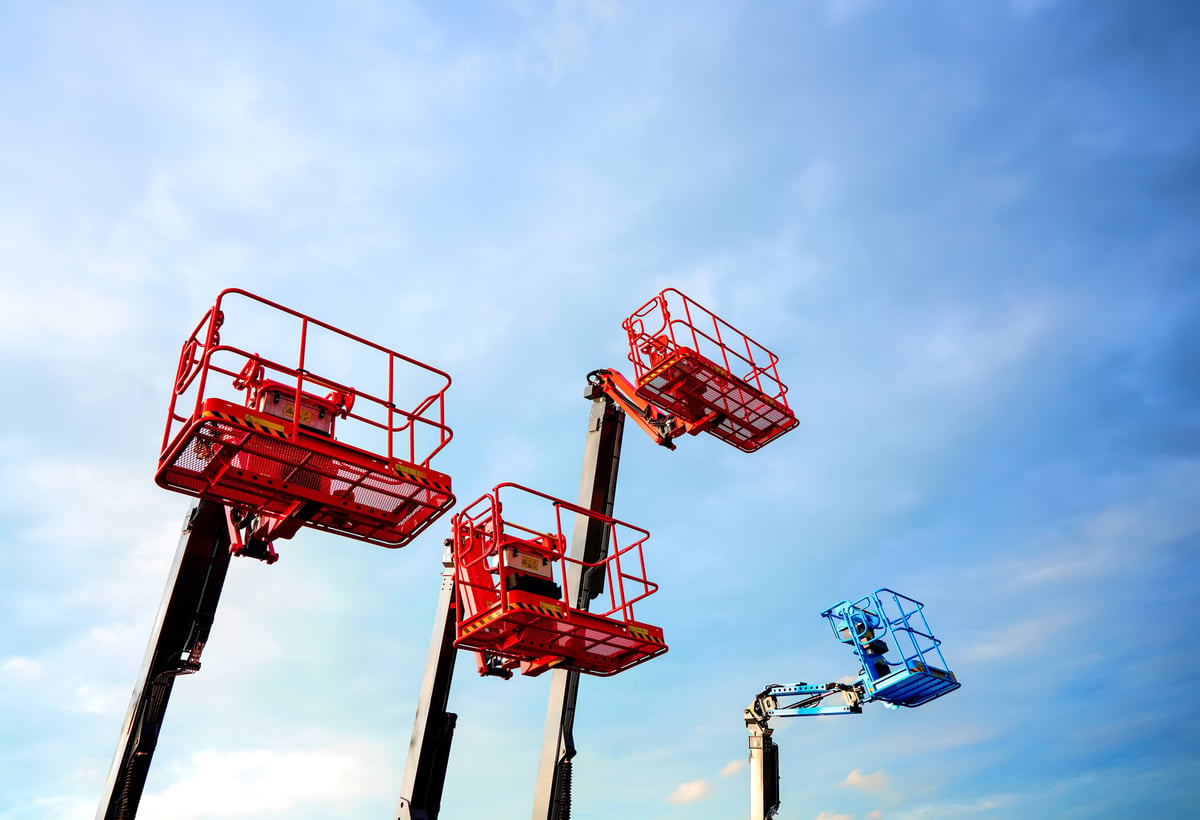 Cherry Pickers on blue sky background. Aerial work platform, lift equipment for construction.