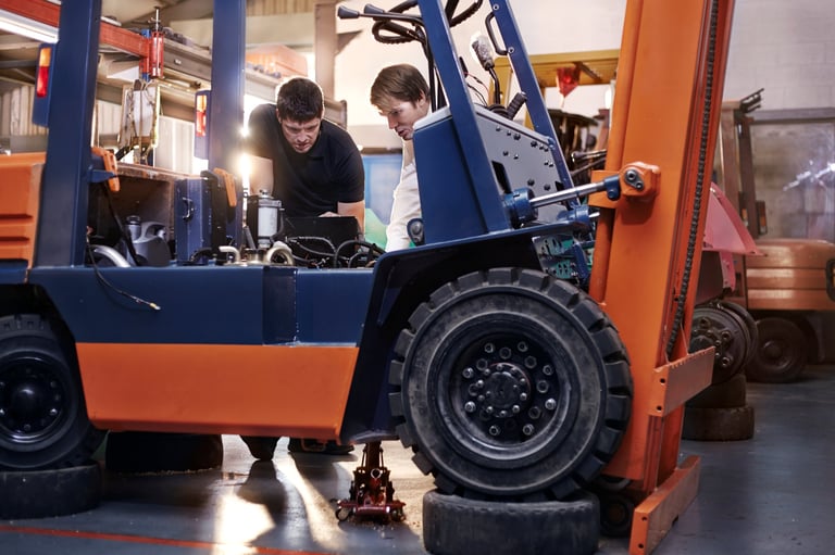 Zwei Techniker reparieren einen Gabelstapler in einer Werkstatt mit Werkzeug